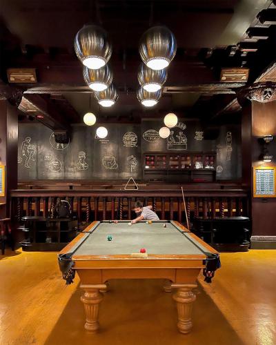 a man playing pool in a room with a table at Chicago Athletic Association, part of Hyatt in Chicago