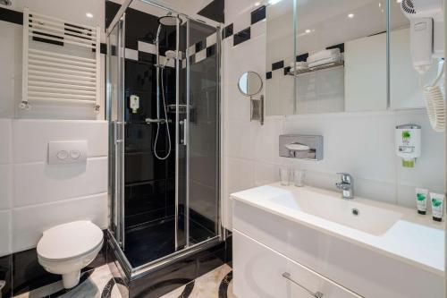a bathroom with a shower and a toilet and a sink at Best Western Plus Celebrity Suites in Vienna