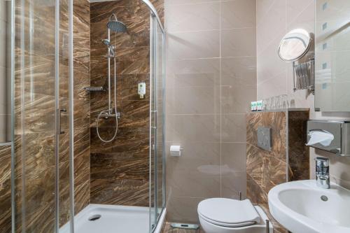 a bathroom with a shower and a toilet and a sink at Best Western Plus Celebrity Suites in Vienna