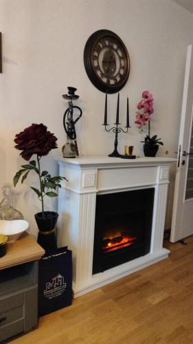 sala de estar con chimenea y reloj en la pared en Apartman KUM, en Vrnjačka Banja