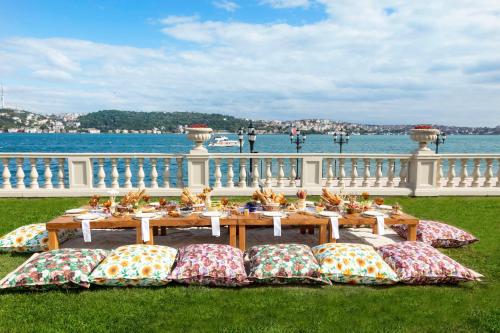 a table with pillows on the grass next to the water at Çırağan Palace Kempinski Istanbul in Istanbul