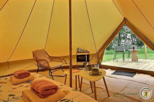 une tente avec deux lits, une chaise et une table dans l'établissement La tente de kergomar, à Ploumilliau