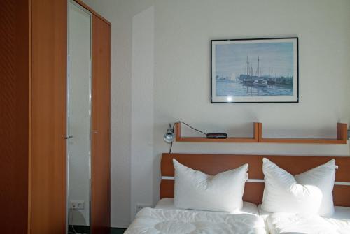 オストゼーバート・ゼリンにあるFerienwohnung "Bellevue" in Sellin auf Rügenのベッドルーム1室(白い枕と絵付)
