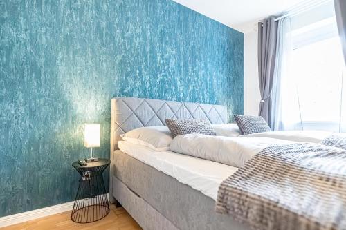 ウィーンにあるNice 1BR & 1LR Apt with Balcony, 9min to City Centerの青い壁の大きなベッドのある寝室