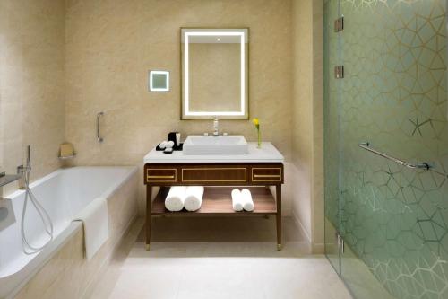 a bathroom with a sink and a tub and a mirror at Grand Hyatt Al Khobar Hotel and Residences in Al Khobar