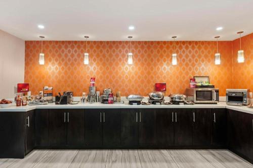 a kitchen with brown cabinets and an orange wall at Best Western Plus Executive Inn in Toronto