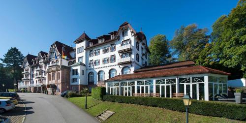 a large white building on the side of a street at Das Palmenwald Schwarzwaldhof, BW Signature Collection in Freudenstadt