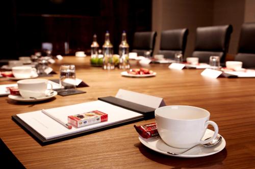 a wooden table with a cup and saucers on it at Hyatt Regency London Albert Embankment in London
