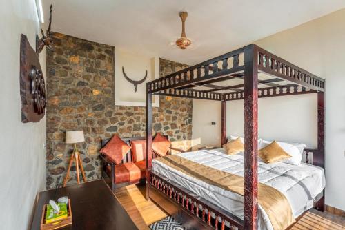 a bedroom with a canopy bed and a stone wall at Cliffpods in Idukki