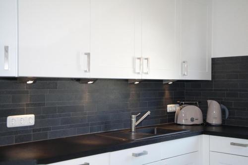 a kitchen with white cabinets and a sink at Dünenresidenz Glowe - Ferienhaus Maxi 200 m zum Strand in Glowe