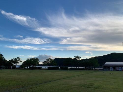 a large grass field with a building and a cloudy sky at 東洋白浜リゾートホテル in Kannoura