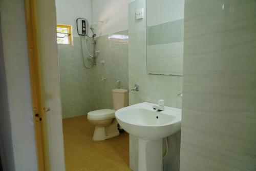 ein weißes Badezimmer mit Toilette und Waschbecken in der Unterkunft Golden Beach Hotel & Restaurant in Trincomalee