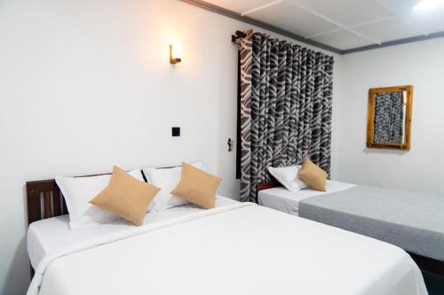 two beds in a room with white walls at Earth and Sky Hotel Nuwara Eliya in Nuwara Eliya