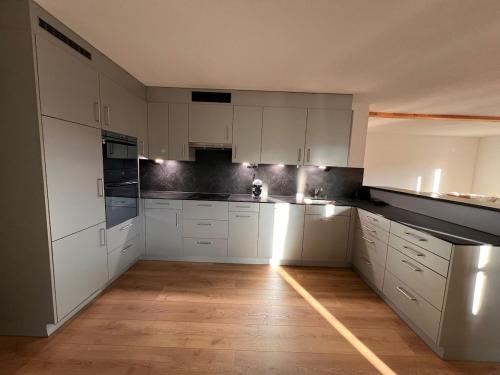 a kitchen with white cabinets and a wooden floor at Ferienwohnung, 4 Personen in Lausen