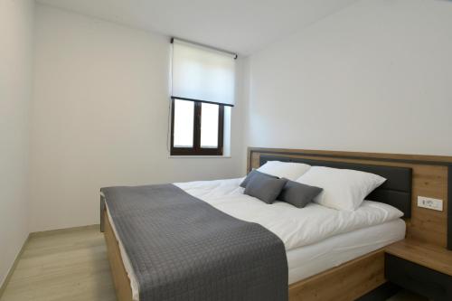 a bedroom with a bed with white sheets and a window at Apartmaji Siliganum in Solkan
