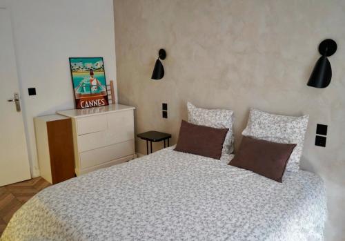 - une chambre avec un lit doté d'oreillers et d'une commode dans l'établissement T2 Appartement 55m2 Terrasse 20m2 - à 15min à pied du Centre Ville - Wifi - Air conditioning, à Cannes