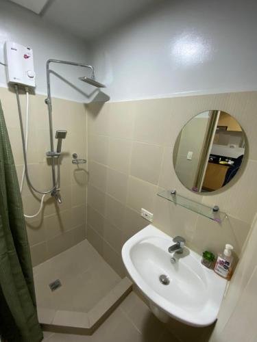 a bathroom with a sink and a shower with a mirror at Theodore Alfonzo rental in Manila