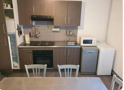 une cuisine avec une table, deux chaises et un four micro-ondes dans l'établissement Appartement Caprunale Rivière & Maquis, à Manso
