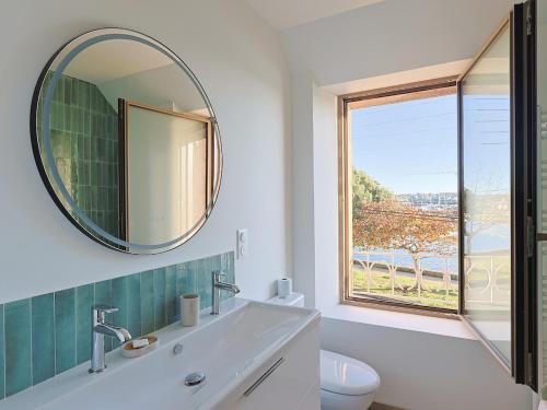 La salle de bains est pourvue d'un miroir, d'un lavabo et d'une fenêtre. dans l'établissement Maison port de Perros-Guirec, à Perros-Guirec