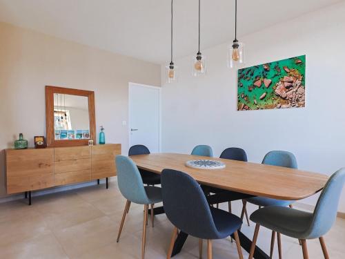 une salle à manger avec une table en bois et des chaises bleues dans l'établissement Maison port de Perros-Guirec, à Perros-Guirec
