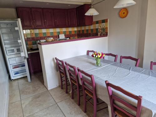 une cuisine avec une table avec des chaises et un réfrigérateur dans l'établissement L'Espitalet, à Arles