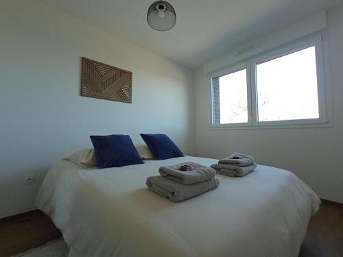 a bedroom with a large white bed with towels on it at Appartement neuf, parking privé, 2 chambres in Bischheim