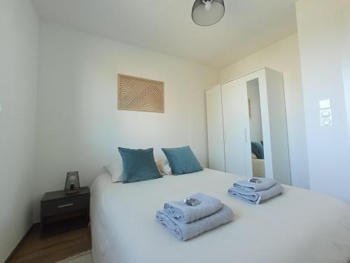a bedroom with a white bed with blue towels on it at Appartement neuf, parking privé, 2 chambres in Bischheim