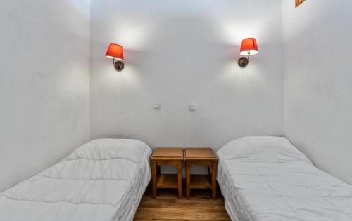 - 2 lits dans une chambre avec des lampes murales dans l'établissement Résidence Les Hauts De Preclaux - Logement 