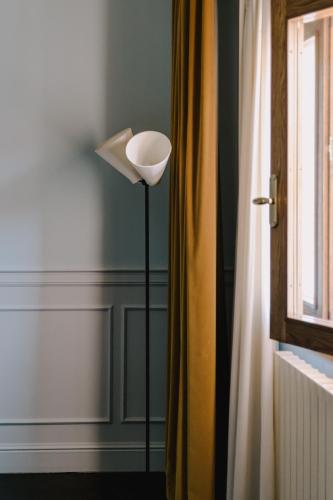 a floor lamp in a room with a window at Maison Matilda - Luxury Rooms in Treviso