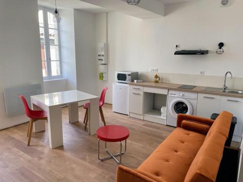 Il dispose d'une cuisine et d'un salon avec une table blanche et des chaises rouges. dans l'établissement Le Coloré- T2 confortable avec vue sur Nérac, à Nérac