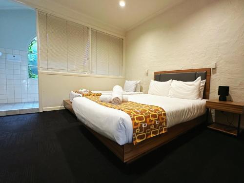 a bedroom with a large bed and a bathroom at Greensborough Motel in Melbourne