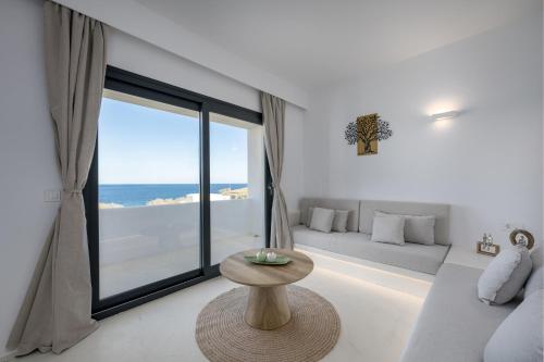 a living room with a table and a large window at San Nectar Luxury Villas in Vourvoulos