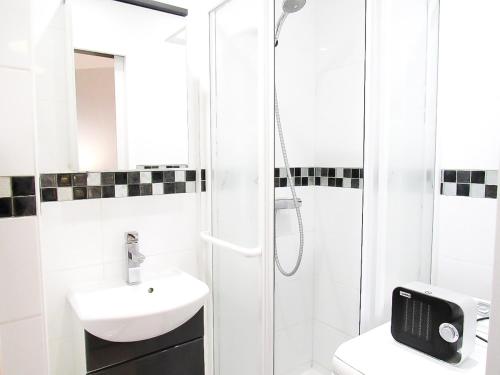 une salle de bain blanche avec une douche et un lavabo dans l'établissement Cosy appartement proche centre, balcon, parking, à Cabourg