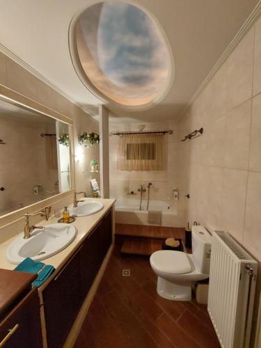a bathroom with two sinks and a toilet and a tub at La maison de Catherine in Volos