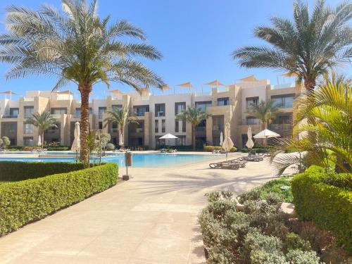 a resort with a swimming pool and palm trees at Cozy 1BD in Mangroovy El Gouna in Hurghada