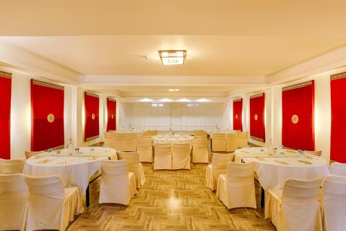 a room with white tables and chairs and red walls at The Chumbi Mountain Retreat & Spa, A Club Mahindra Associate in Pelling