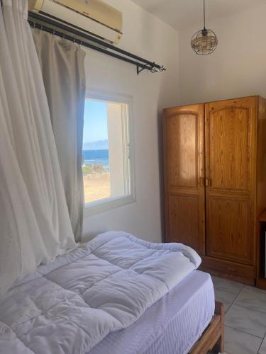 a bedroom with a bed and a window with the ocean at Dahab Lodge in Dahab