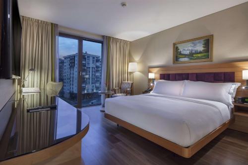 a bedroom with a large white bed and a large window at DoubleTree by Hilton Trabzon in Trabzon