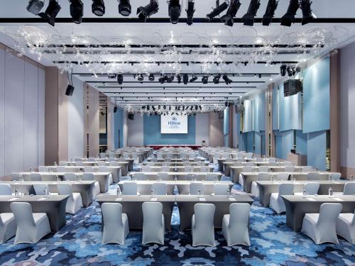 a room with rows of tables and white chairs at Hilton Taipei Sinban in Taipei