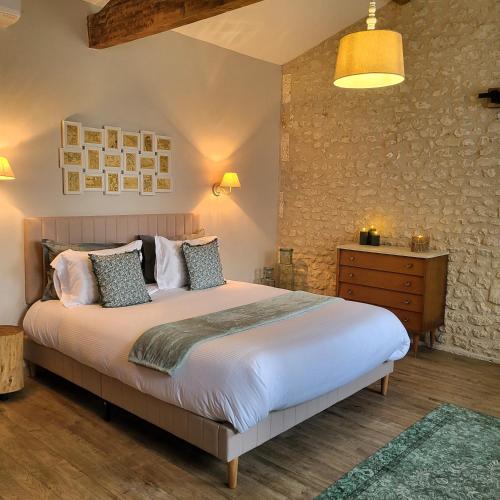 une chambre avec un grand lit et un mur en pierre dans l'établissement Gîte Le petit Chemin, à Challignac