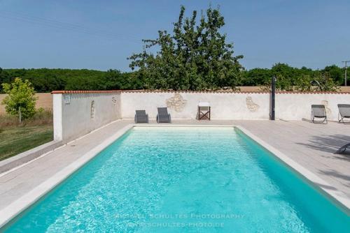 une piscine avec deux chaises et une table dans l'établissement Gîte Le petit Chemin, à Challignac