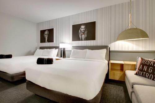 a hotel room with two beds and a couch at The Rose Chicago, Tapestry Collection By Hilton in Rosemont