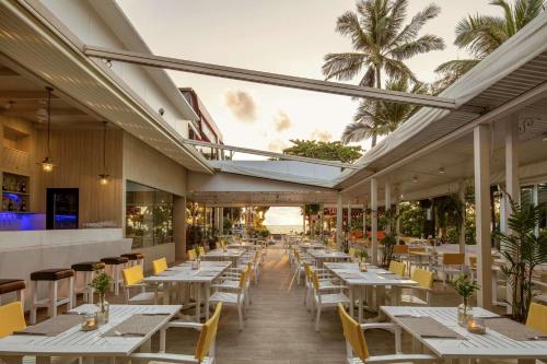 a restaurant with white tables and chairs and palm trees at DoubleTree by Hilton Phuket Banthai Resort in Patong Beach