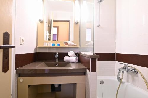 une salle de bain avec un lavabo, une baignoire et un miroir dans l'établissement Anémone, à Saint-Raphaël