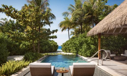a resort pool with chairs and a view of the ocean at Waldorf Astoria Maldives Ithaafushi in South Male Atoll