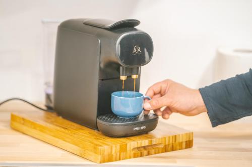 une personne verse une tasse dans une cafetière dans l'établissement Face à la cité, Terrasse Et Climatisation - AE, à Carcassonne