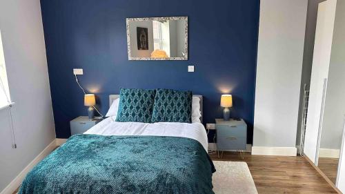 a blue bedroom with a bed and a mirror at Spacious and homely city centre studio in Coventry