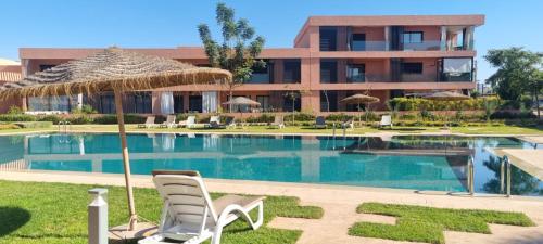 une piscine avec deux chaises et un parasol dans l'établissement Appartement Domaine de Noria, à Marrakech