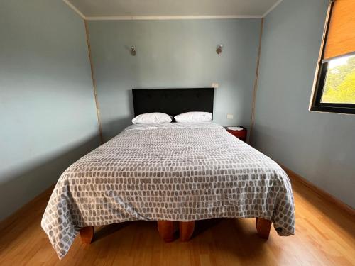 a bedroom with a bed with a blanket on it at Los Molinos Alto in Valdivia