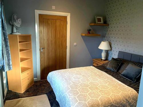 a bedroom with a bed and a wooden door at Y Caban-The Cabin-2 Guests-Private Parking-Fast WIFI in Llanelli